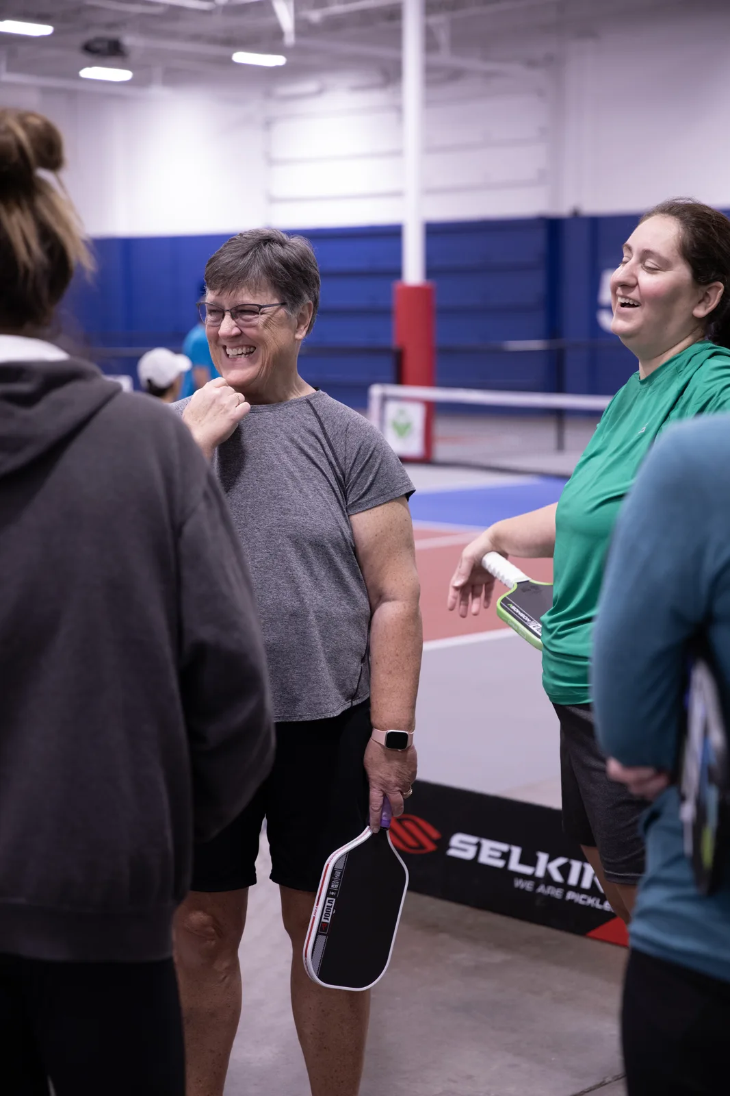 Players chatting with paddles beside the courts